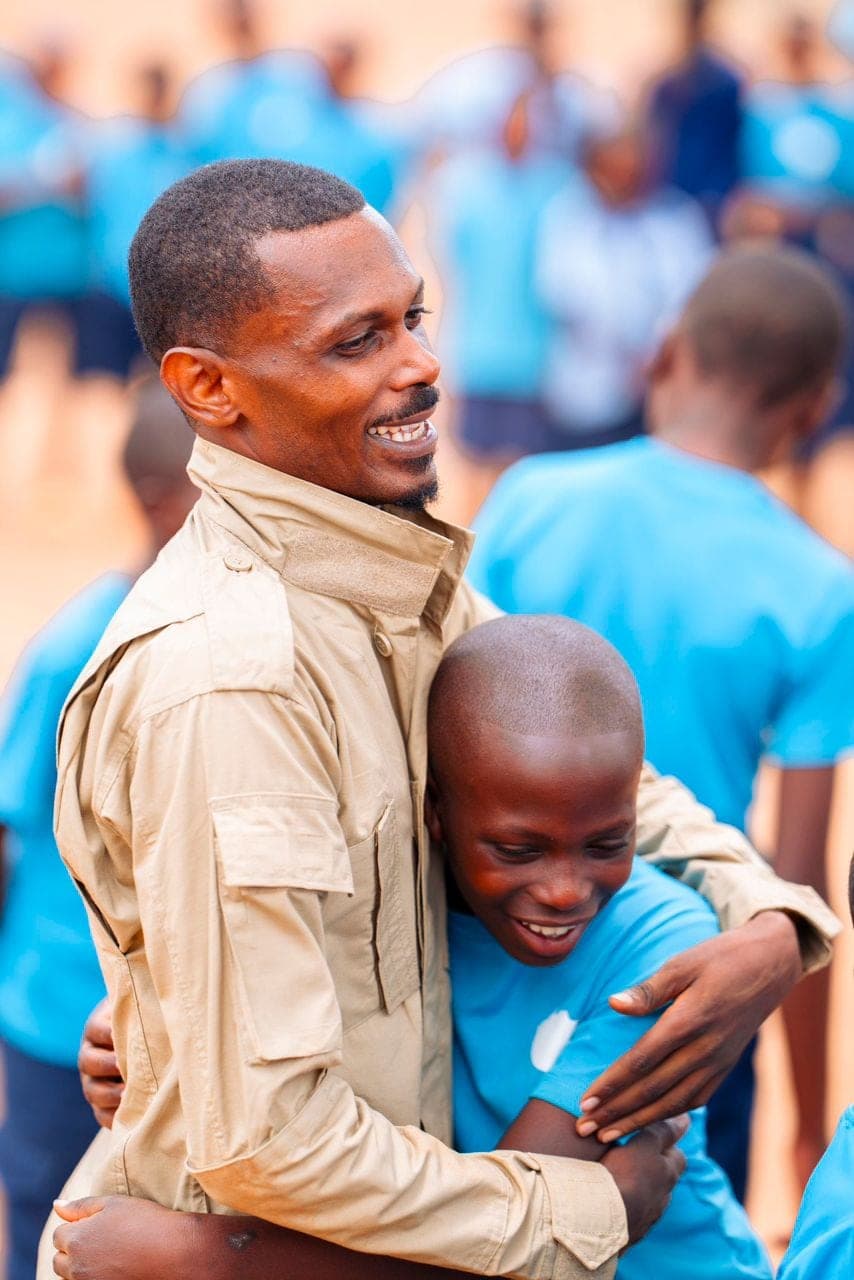 Cyusa Ian Berulo embracing a child at a community gathering