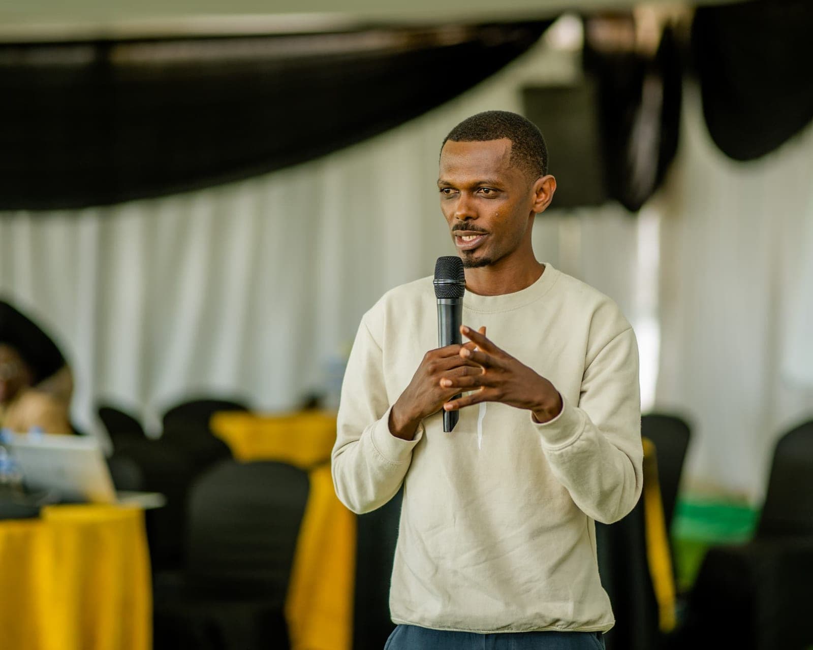 Cyusa Ian Berulo speaking into a microphone at an event